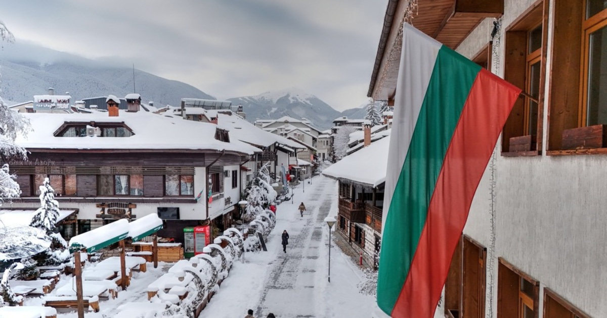 image of a snowy Bansko town street from the town square with a Bulgarian flag in the shot